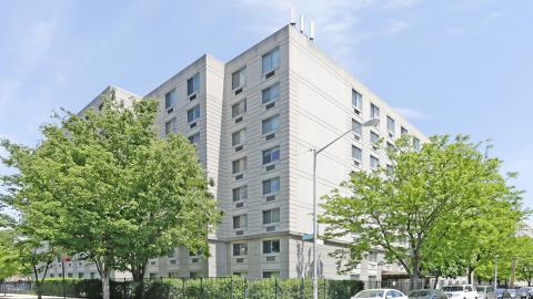 Two eight-story buildings with a white facade stand tall in Corona, Queens.