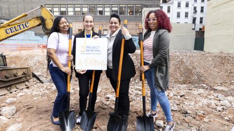 four women holding shovels on the dig site of the development